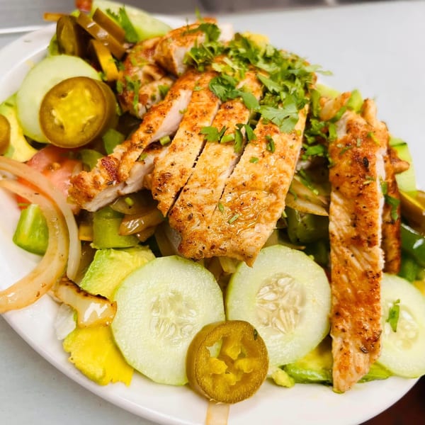 Grilled chicken salad with cucumbers, avocado, onions, tomatoes, and pickled jalapeños.
